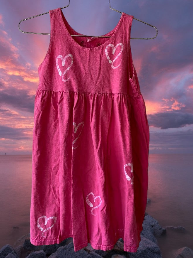 This girl's pink dress features a sleeveless design with a heart pattern making it a perfect dress for summer