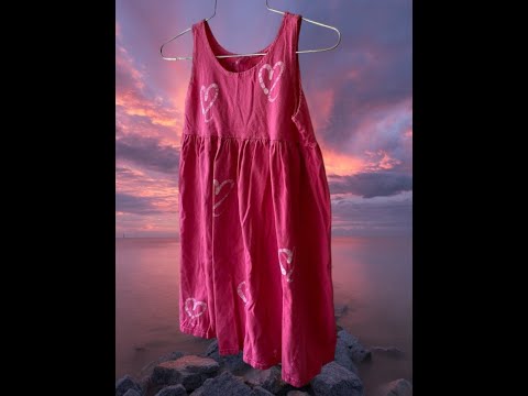 This girl's pink dress features a sleeveless design with a heart pattern making it a perfect dress for summer